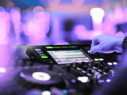 Mano su mixer, luci viola e rosa sfocate, creando l'atmosfera perfetta per la musica tech house.