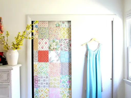 Kreatives Basteln mit Tapetenresten: Ein Patchwork-Muster ziert die Tür eines Schranks. Daneben hängt ein hellblaues Kleid.
