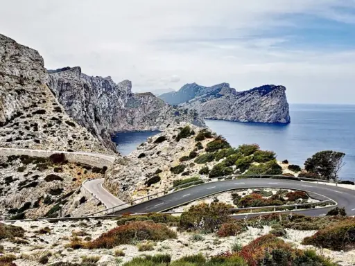 Carretera sinuosa en acantilados rocosos con vistas al mar azul. Un viaje en coche por un paisaje espectacular.