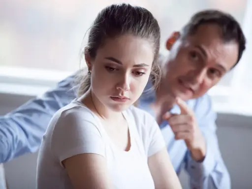 Mujer triste, hombre la señala. Una escena que evoca el trauma bonding español, donde el dolor crea un vínculo perverso.