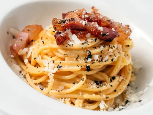 Pyszna carbonara z chrupiącym boczkiem, posypana parmezanem i pieprzem. Idealny boczek do carbonary to klucz do sukcesu.