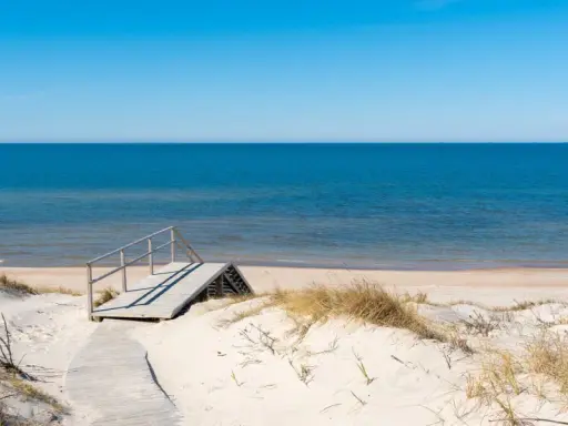 Drewniane schody prowadzące na piaszczystą plażę nad spokojnym Bałtykiem.