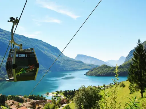 Cabina panoramica sul lago di Molveno, con montagne sullo sfondo. Si intravede una cascata tra gli alberi.