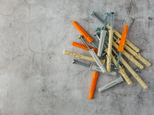Montón de tacos de pared de varios colores (naranja, beige, gris) con tornillos. Listos para fijar cualquier cosa a la pared.