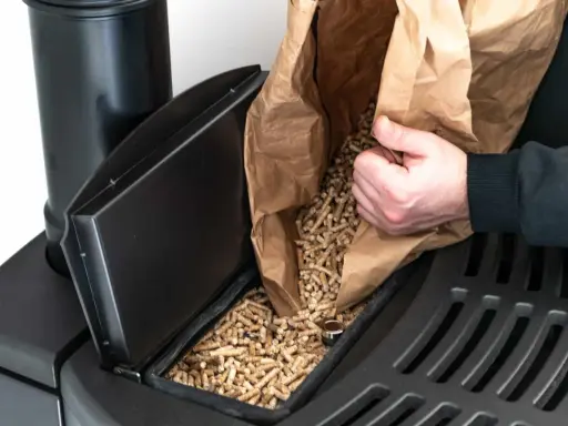 Persona rellena el depósito de una estufa de pellets con combustible.