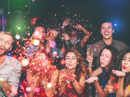 Gente celebrando con confeti y copas de champán. ¡Una fiesta perfecta para organizar despedida de soltero!