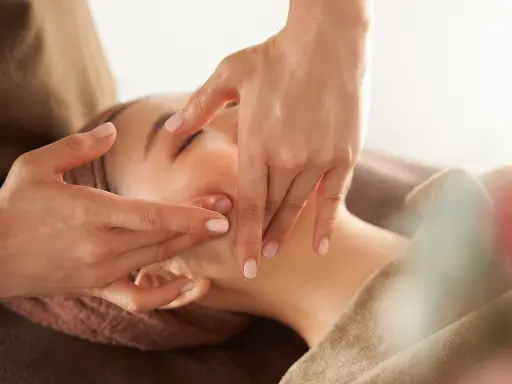 Manos expertas realizan un **dibujo masaje facial paso a paso**, aplicando suaves presiones en el rostro de una mujer para relajarla.