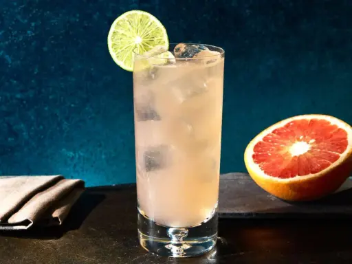 Erfrischender Greyhound Cocktail mit Eis, Limettenspalte und Grapefruit-Hälfte.