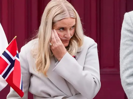 Kronprinsessan Mette-Marit med syrgasgrimma, en påminnelse om hennes sjukdom, håller en norsk flagga.
