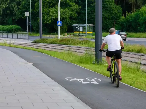 Mężczyzna na rowerze na ścieżce, obok torów tramwajowych. Uważaj, bo mandat za prowadzenie roweru pod wpływem alkoholu jest wysoki.