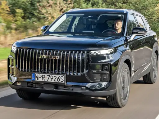 Czarny Jaecoo 7 w ruchu, z kierowcą za kierownicą. Sprawdź aktualną jaecoo 7 cena i dowiedz się więcej o tym SUV-ie.
