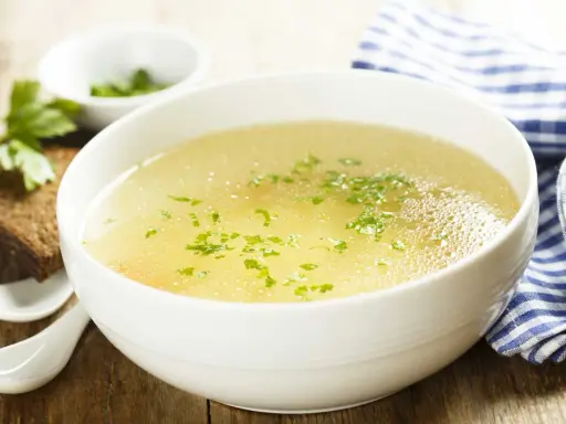 Aromaticzny rosół z perliczki, ozdobiony natką pietruszki, podany z kromką chleba. Idealny na chłodne dni.