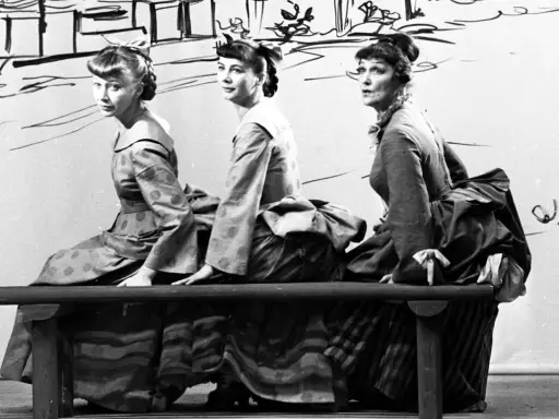 Trzy kobiety w historycznych strojach siedzą na ławce. Czy jedna z nich to guwernantka, która pilnuje porządku?