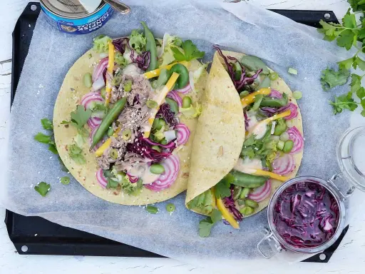 Två läckra tonfisk wraps fyllda med grönsaker, rödlök och en krämig sås. En burk med rödkålssallad står bredvid.