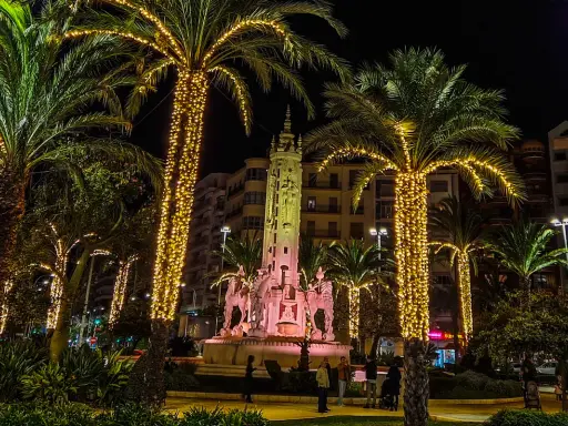 Nocna iluminacja palm i fontanny z rzeźbami. Wspaniała atmosfera, jakby trwały święta w Hiszpanii.