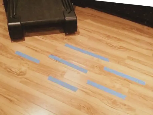 Marcando con cinta azul las áreas del suelo laminado que necesitan reparar.