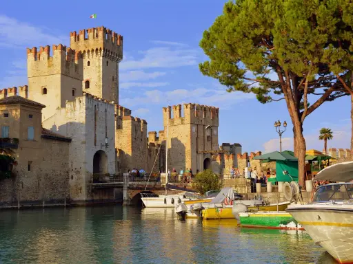 Castello Scaligero sul lago, ideale per vacanze in Lombardia. Barche ormeggiate in un porto pittoresco.