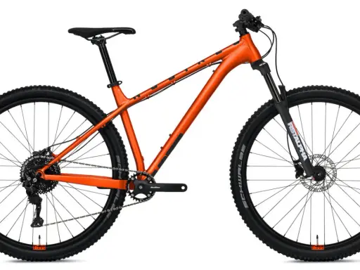 Pomarańczowy rower górski z amortyzowanym widelcem. Czy to hardtail czy full? Ten model to klasyczny hardtail, gotowy na wyzwania.