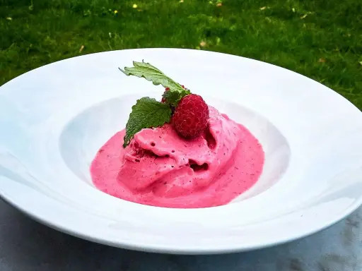 Hallonglass i en vit skål, toppad med hallon och mynta. Perfekt för ett enkelt hallonglass recept.