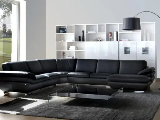 Sofá modular negro de cuero, con mesa de centro de cristal y estanterías blancas. Un diseño de gran dimensión.