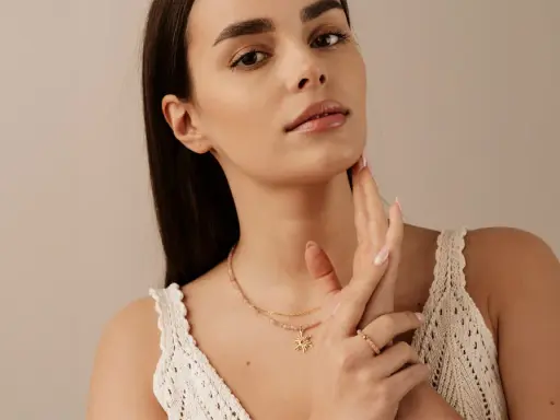 Delikatny choker z zawieszką w kształcie słońca, noszony przez kobietę z subtelnym makijażem.