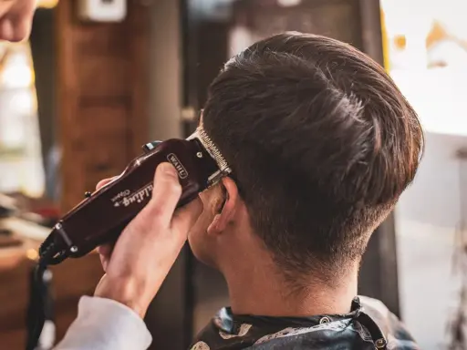 Stylista pokazuje, jak obciąć włosy maszynką, tworząc modne cięcie.
