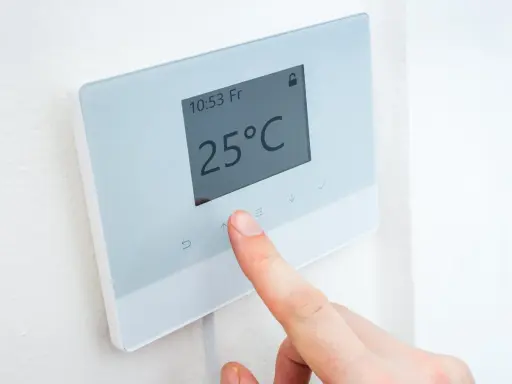 Dedo ajustando uno de los tipos de termostatos para calefacción, mostrando 25°C.