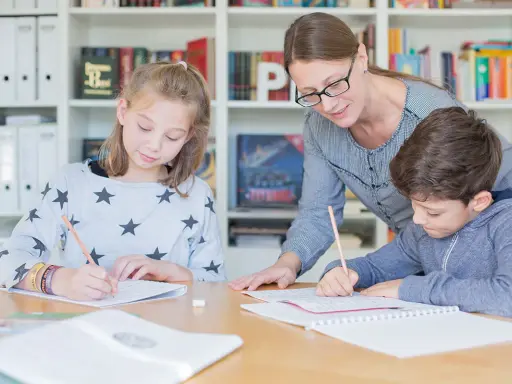 Lehrerin hilft zwei Schülern bei der Nachhilfe Realschule. Sie schreiben konzentriert in ihre Hefte.