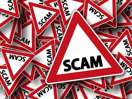 Viele rote Dreiecke mit der Aufschrift "SCAM" stapeln sich. Vorsicht vor der aktuellen Online-Betrugsmasche!