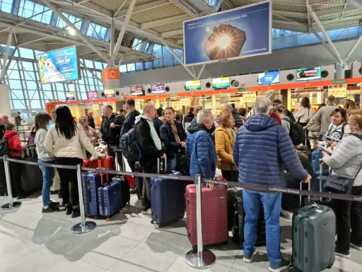 Kolejka do odprawy na jednym z największych lotnisk w Polsce. Pasażerowie z bagażami czekają na swoją kolej.