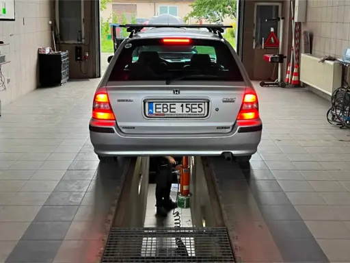 Srebrny kombi Honda Civic na podnośniku w warsztacie. Zastanawiasz się, ile kosztuje przerejestrowanie samochodu?