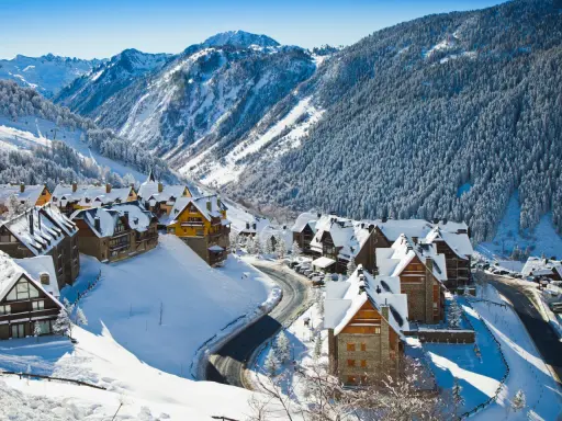 Pueblo nevado en los Pirineos, ideal para saber donde ir en el puente de diciembre. Casas de piedra y madera cubiertas de nieve, rodeadas de bosques y montañas.
