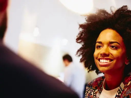 Donna sorridente in primo piano, discute idee per capire che lavoro fare a 40 anni senza esperienza.