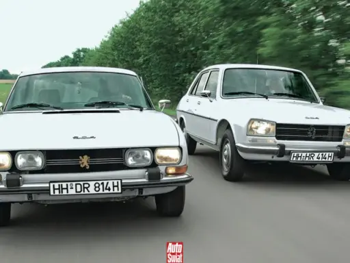 Dwa białe Peugeot 504 jadące obok siebie po wiejskiej drodze.