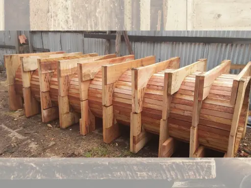 Encofrados de madera apilados, listos para dar forma a grandes estructuras circulares.