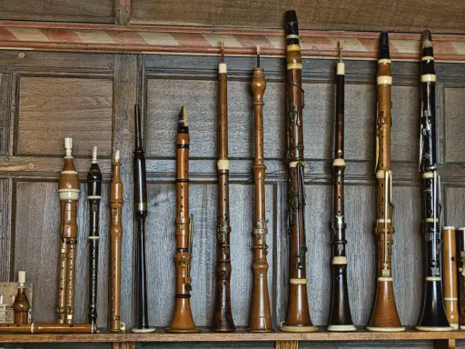 Une collection d'instruments à vent anciens, une véritable famille des vents, alignés sur un mur boisé.