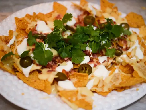 En härlig nachotallrik i ugn med smält ost, bacon, jalapeños och färsk koriander. Perfekt för en mysig kväll!