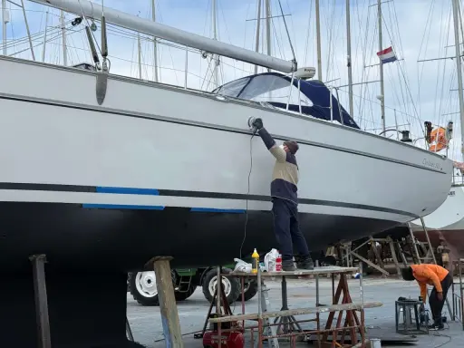 Mann poliert mit Schleifmaschine die Yacht. Edelstahl-Teile glänzen nach der Arbeit.
