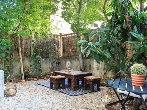 Un angolo relax per il tuo progetto giardino 50 mq: tavolino in legno intagliato, sgabelli, lanterne e un cactus vivace.