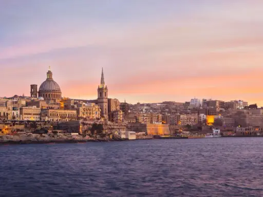 Valletta, Malta, im Dezember bei Sonnenuntergang. Das malerische Malta Wetter im Dezember zeigt sich hier von seiner schönsten Seite, mit warmen Farben am Himmel über der historischen Stadt.