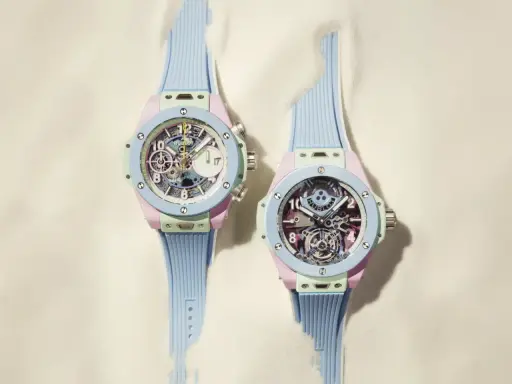 Due orologi con cinturino azzurro e cassa color pastello, con un intricato calibro di manifattura visibile sul quadrante.