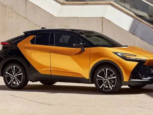 Nowy Toyota C-HR GR w kolorze pomarańczowo-czarnym, z dynamiczną linią nadwozia, zaparkowany przy betonowej ścianie.