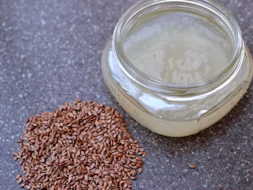 Graine de lin pour rajeunir : une poignée de graines de lin brunes à côté d'un pot en verre rempli d'un gel clair, peut-être un sérum fait maison.