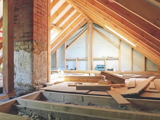 Aménagement des combles : début de la création d'un plancher avec des poutres en bois et des matériaux de construction.