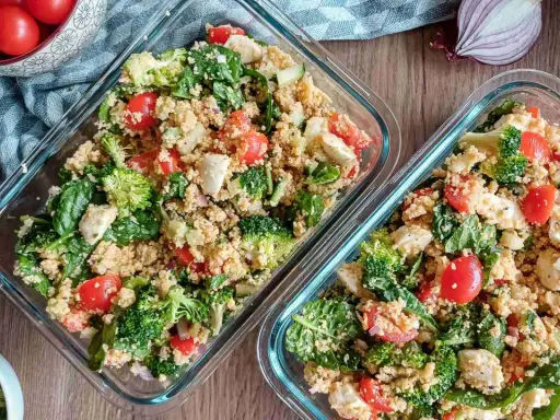 Zwei Behälter mit Couscous-Salat, reich an Couscous-Protein, gefüllt mit Brokkoli, Tomaten, Spinat und Mozzarella.