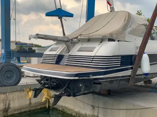 Ein luxuriöses Motorboot wird für das Winterlager aus dem Wasser gehoben. Zwei goldene Propeller ragen aus dem Rumpf.