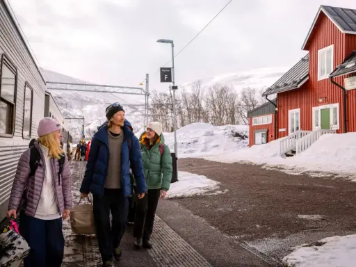 Tre vänner anländer till Björkliden med tåg, redo för vinteräventyr. En röd stationsbyggnad och snöklädda berg vittnar om att de är framme vid en av Sveriges mest natursköna platser, inte långt från evens flygplats.