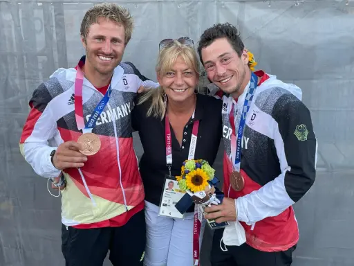 Tatjana Pokorny mit zwei Medaillengewinnern des Team Deutschland bei den Olympischen Spielen in Tokio.