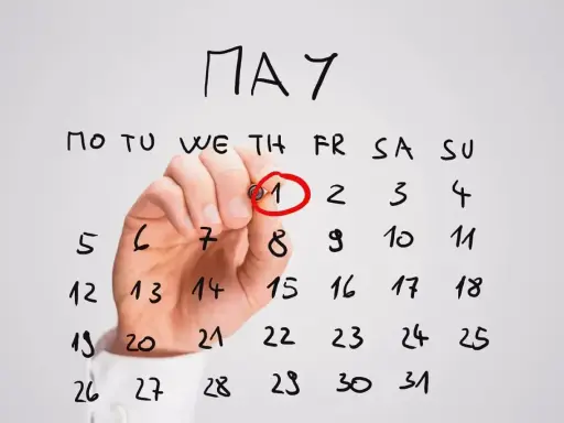 Ręka zakreśla czerwonym pisakiem datę 1 maja na kalendarzu. To ważne awizo, początek miesiąca.