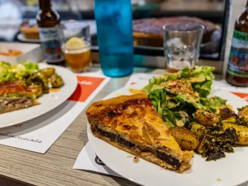 Tranche de pâté en croûte, spécialité Limoges, servie avec salade et pommes de terre rôties.
